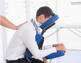 Man in an office receives an upper back massage from a certified massage therapist.